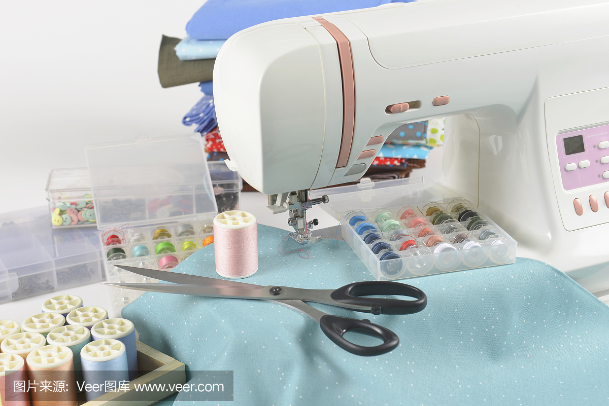 缝纫机和彩色线卷,剪刀,织物和配件,用于缝纫的白色背景,缝纫和针绣概念。(选择性聚焦)